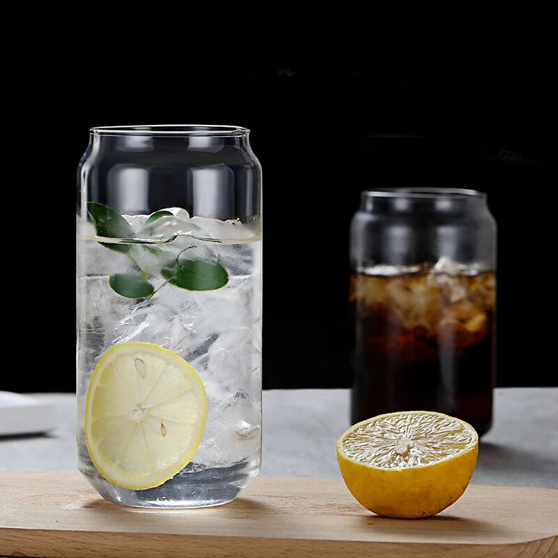 Clear glass tumbler with lemon and ice on a wooden surface, with another glass in the background.