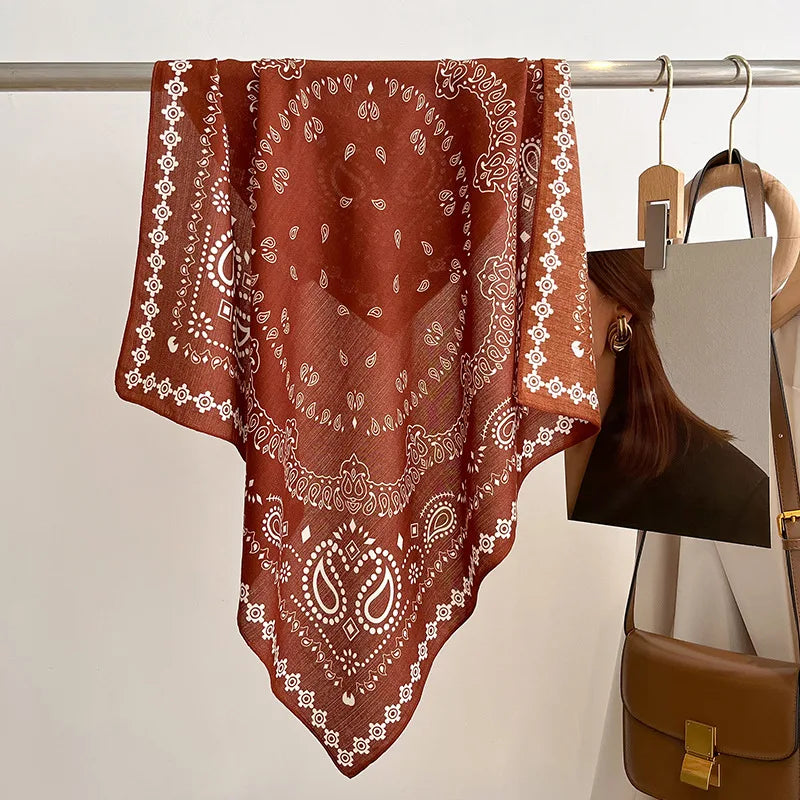 Brown bandana with white patterns draped over a rack against a neutral background
