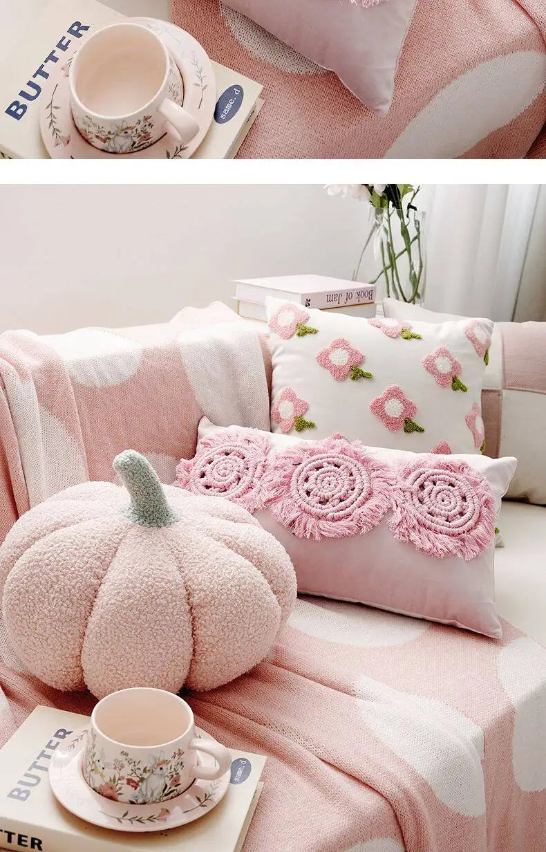 Pink sofa with decorative pillows and a pumpkin-shaped cushion on a soft pink blanket.