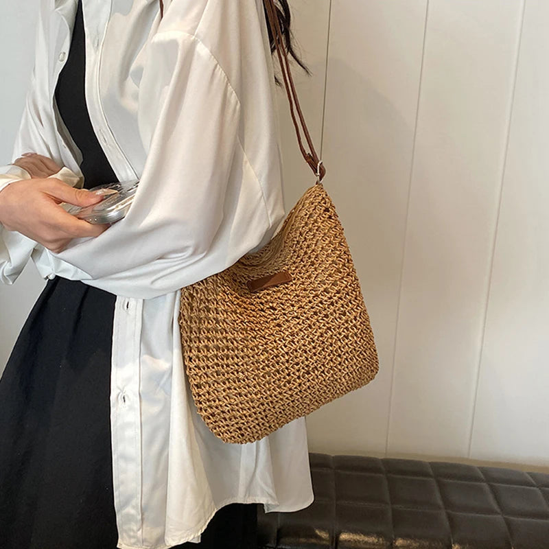 Person holding a woven handbag against a neutral background