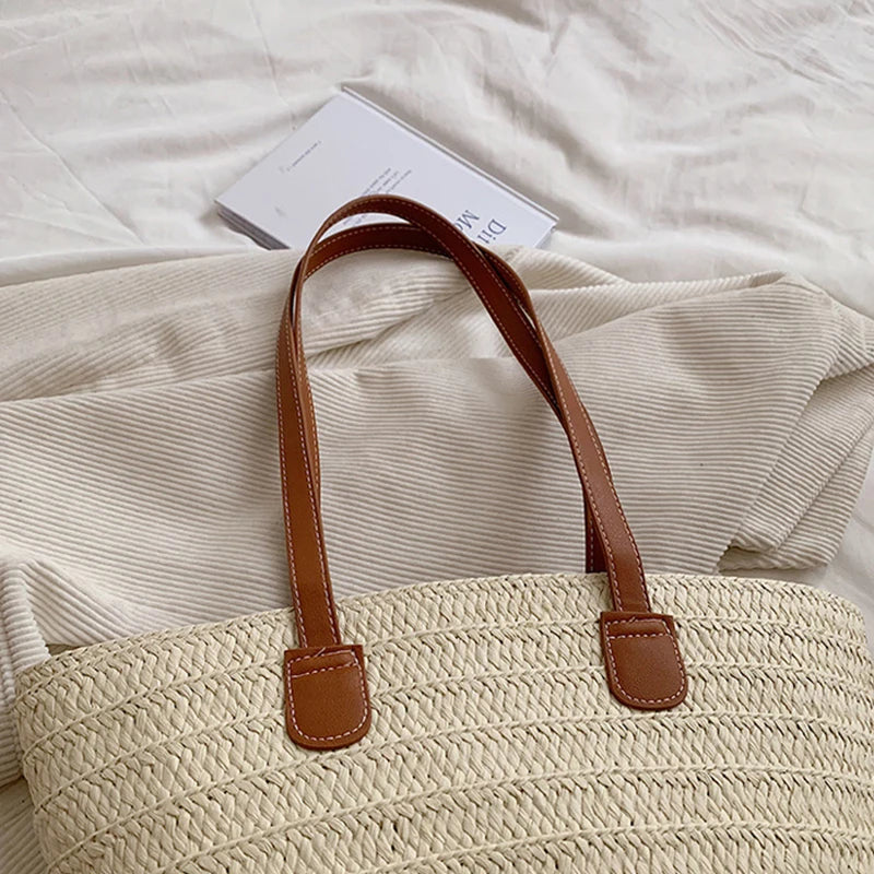 Beige woven bag with brown handles on a textured surface