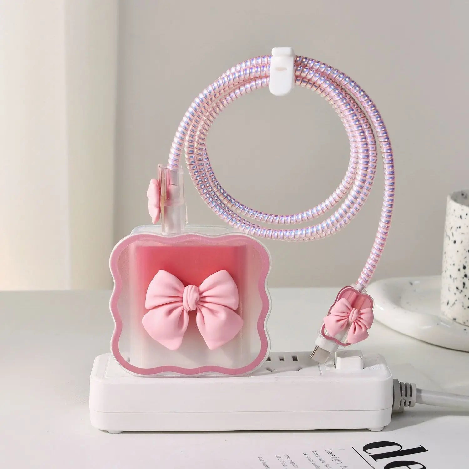 Pink phone charger with a bow and floral design on a white surface.