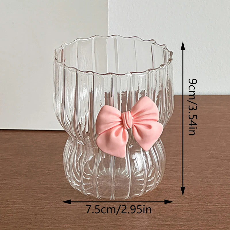 Clear glass vase with a pink bow decoration on a wooden surface, showing measurements.