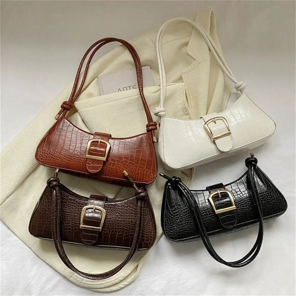 Four handbags in brown, white, black, and brown with a gold buckle on a light background.