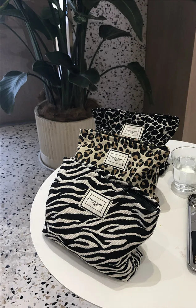 Leopard print bags on a round white table with a plant and glass in the background