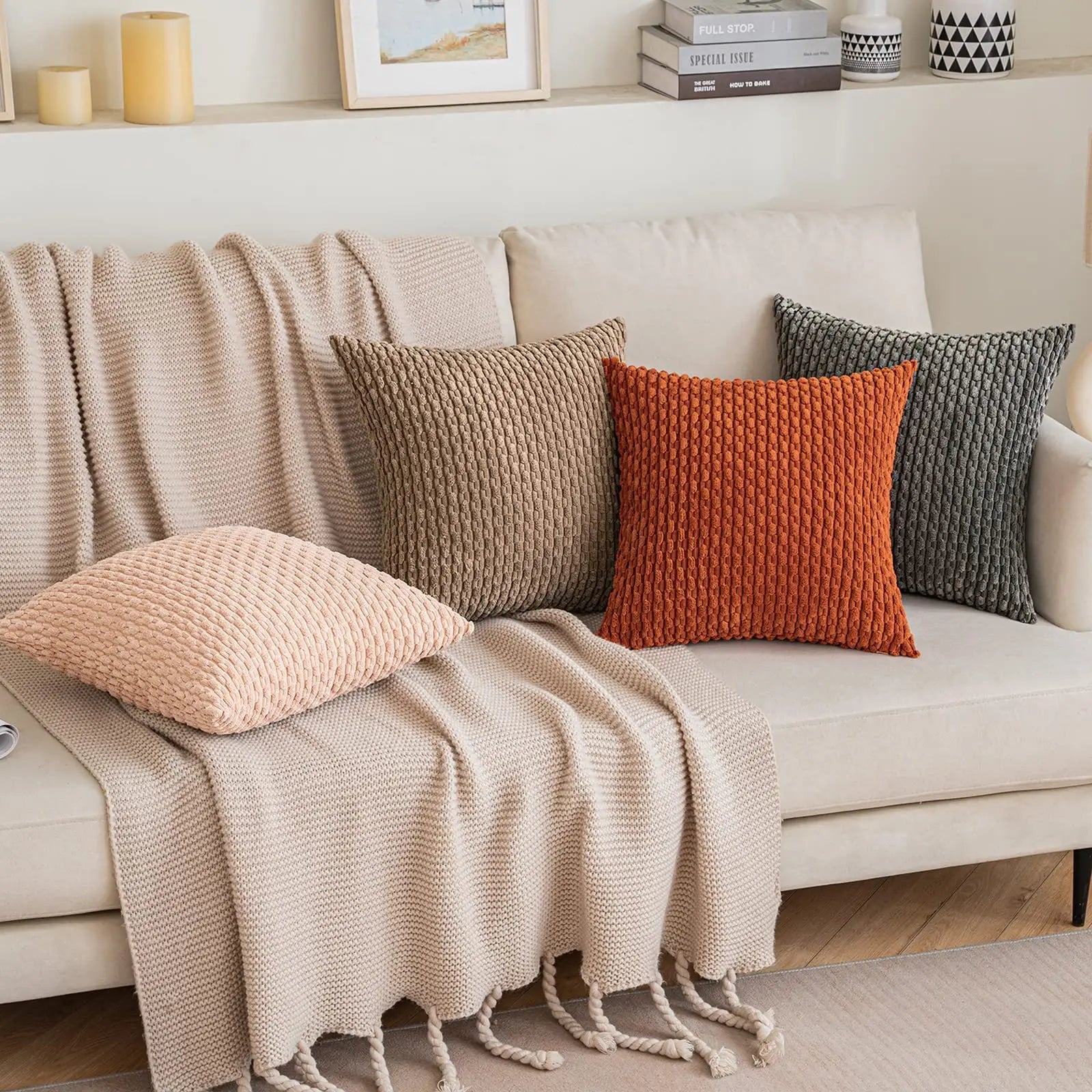 Beige sofa with knitted throw and colorful cushions in a cozy living room setting.