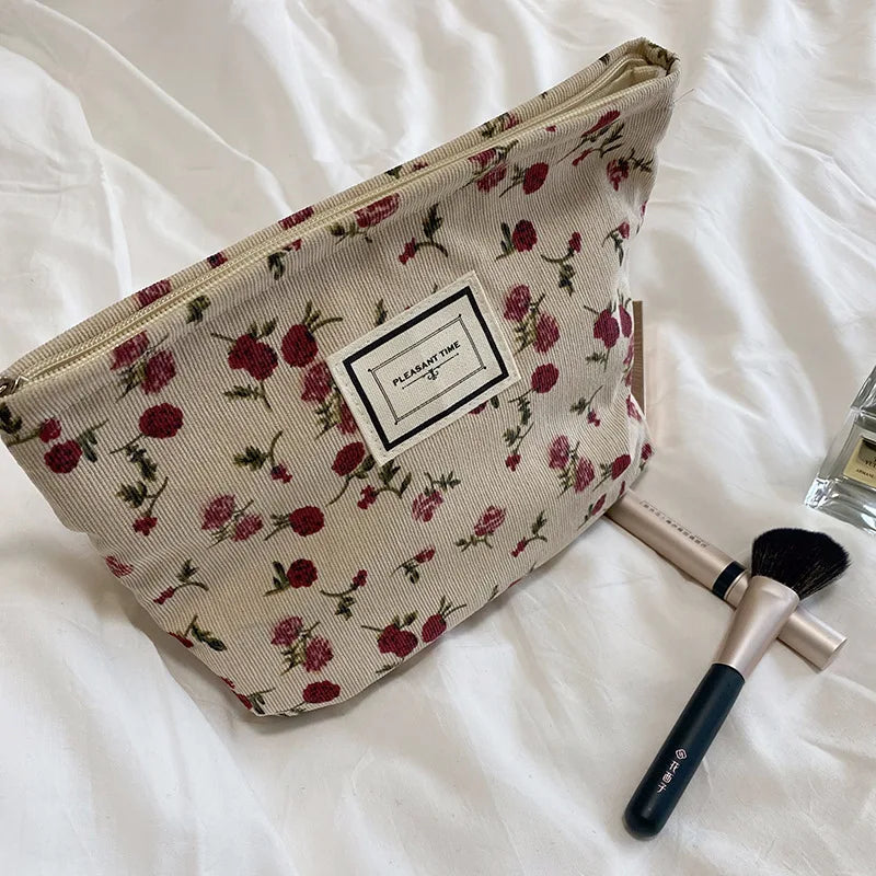 Floral-patterned makeup bag with brushes on a white surface