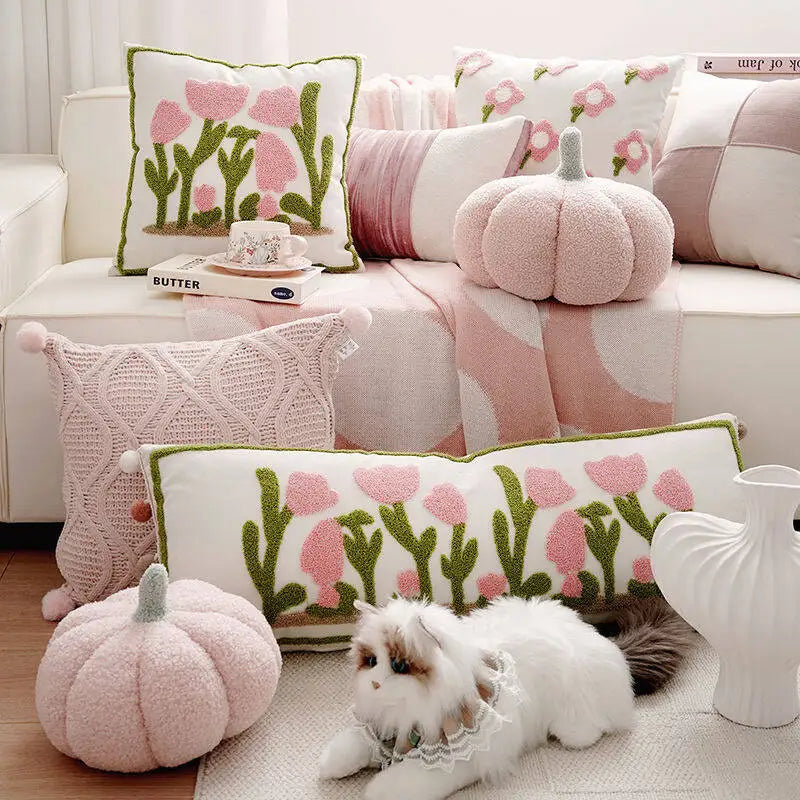 Decorative pillows with floral patterns on a sofa with pumpkins and a dog.