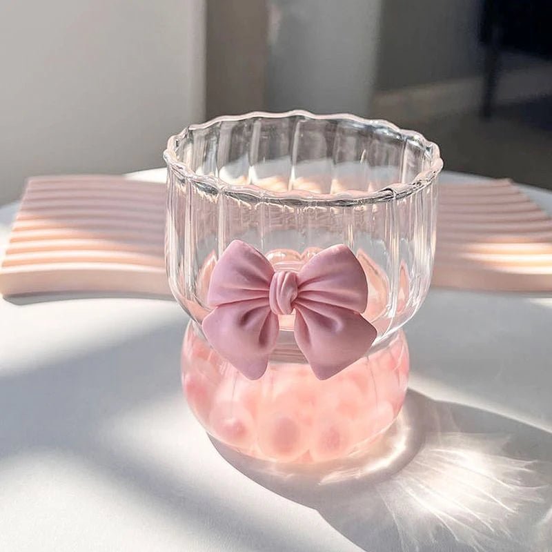 Clear glass container with pink bow and pink liquid on a light surface