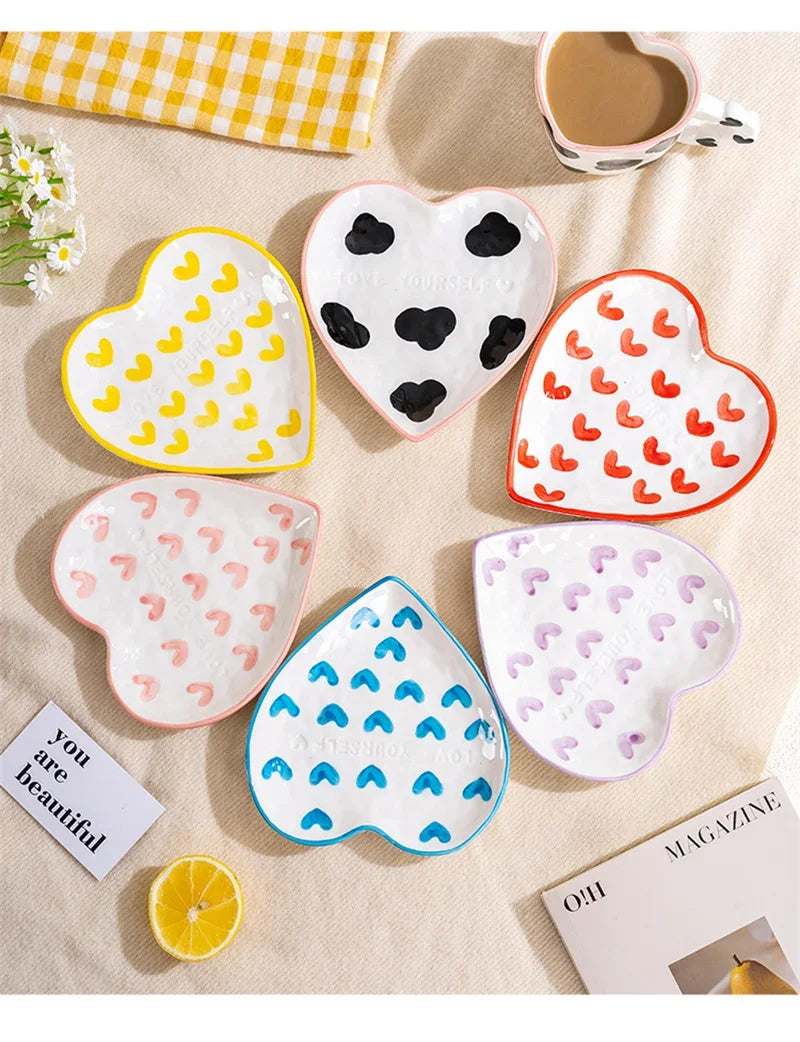 Heart-shaped ceramic coasters with colorful patterns on a table with a magazine and lemon.