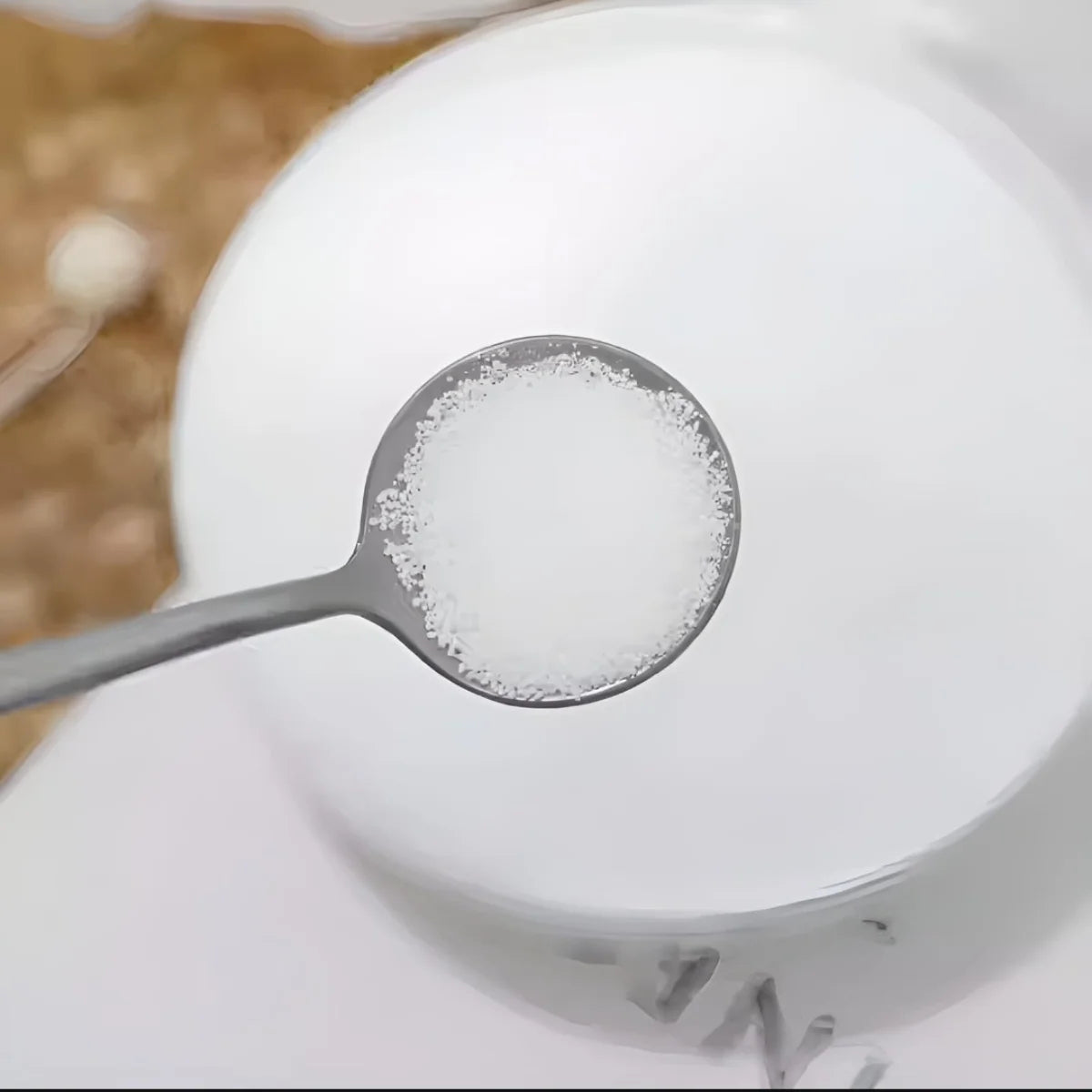 Spoonful of candle wax over a bowl with a blurred background