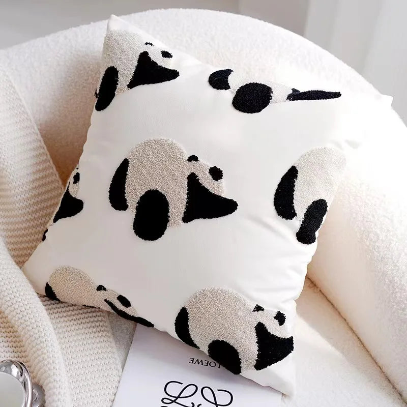 White pillow with black panda patterns on a white surface
