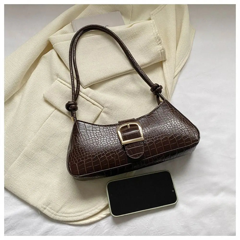 Brown handbag with a phone on a white surface