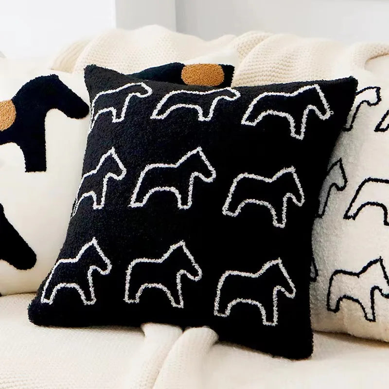 Black pillow with white horse patterns on a beige couch