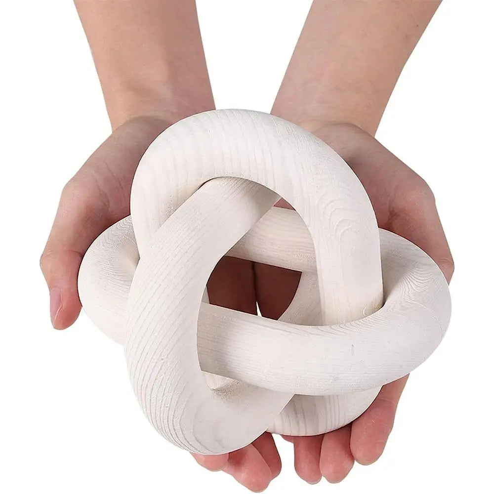 White decorative knot held by hands against a white background