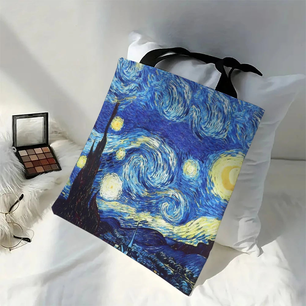Tote bag with 'Starry Night' design on a bed with makeup and glasses.