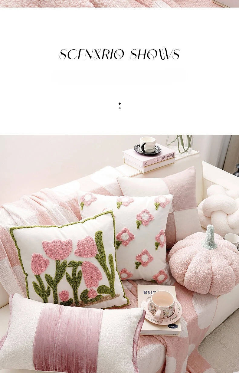 Pink and white floral cushions on a sofa with a pumpkin decoration.