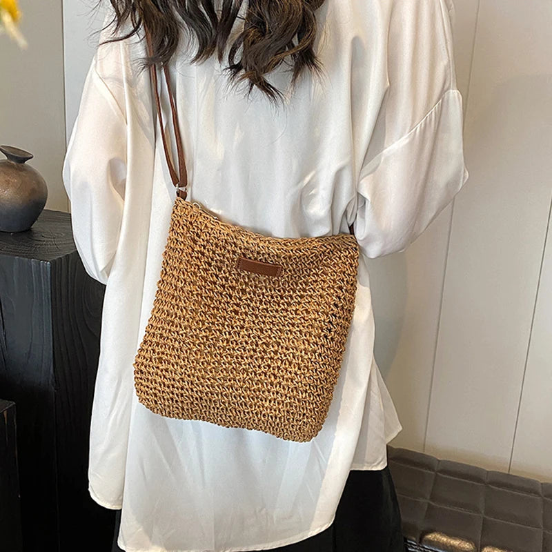 Person wearing a white shirt with a brown woven bag over the shoulder indoors.