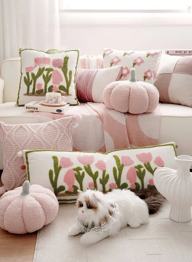 Decorative pillows with floral and cactus patterns on a sofa, with a small dog lying on the floor.