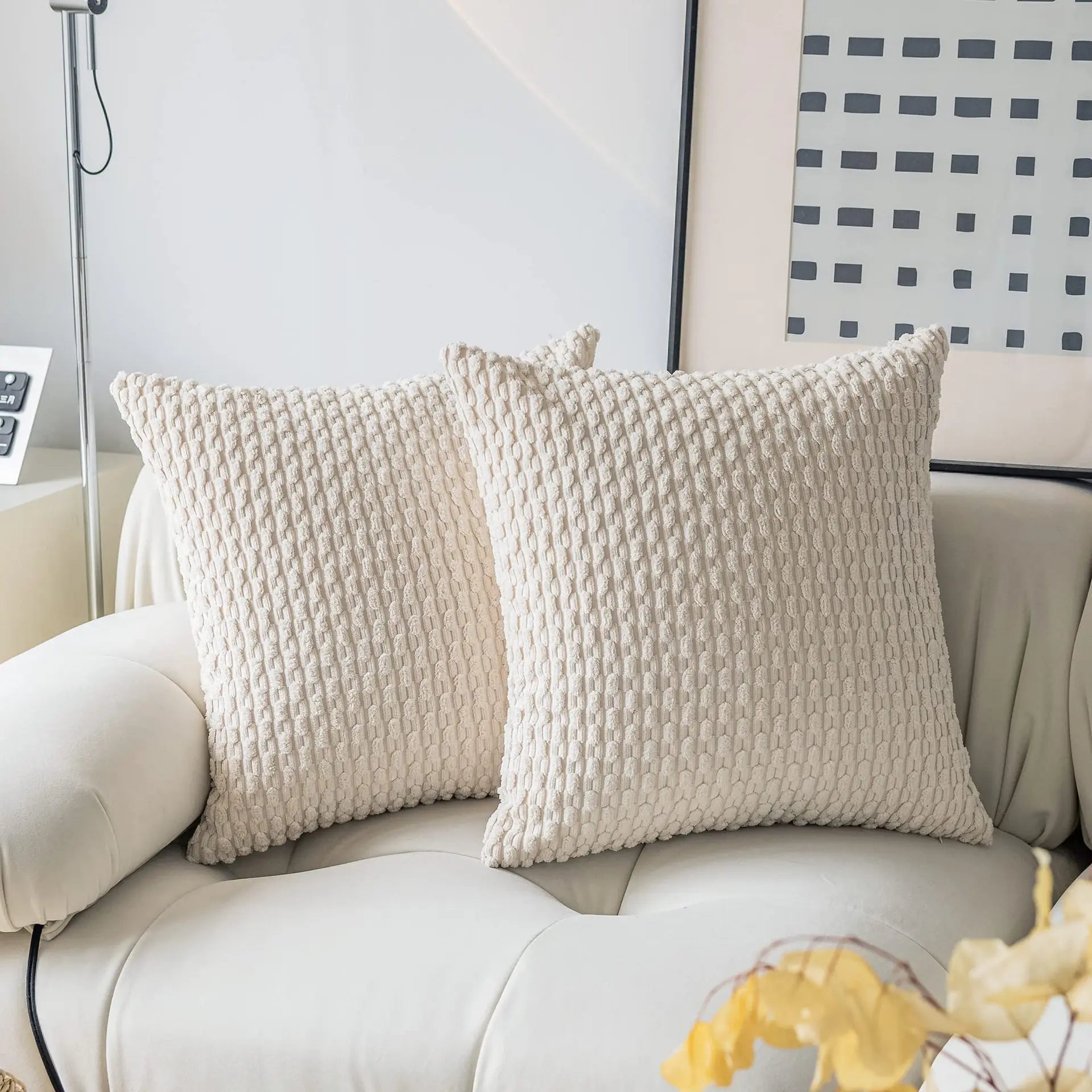 Two textured pillows on a white sofa with a decorative wall in the background