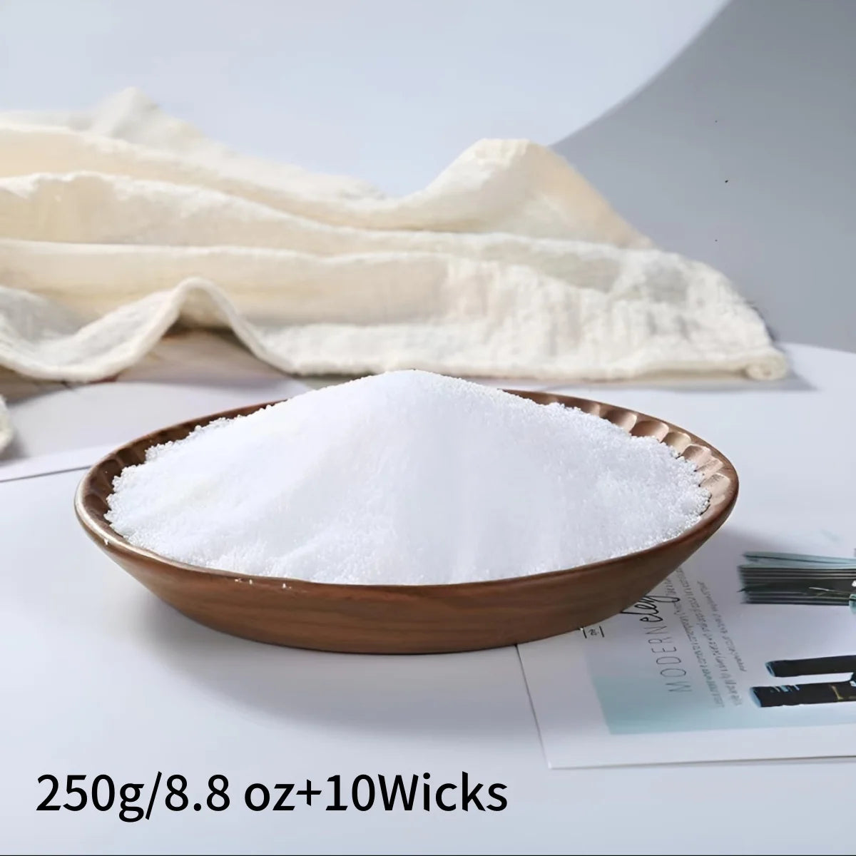 Brown bowl filled with candle wax on a newspaper with a white cloth in the background