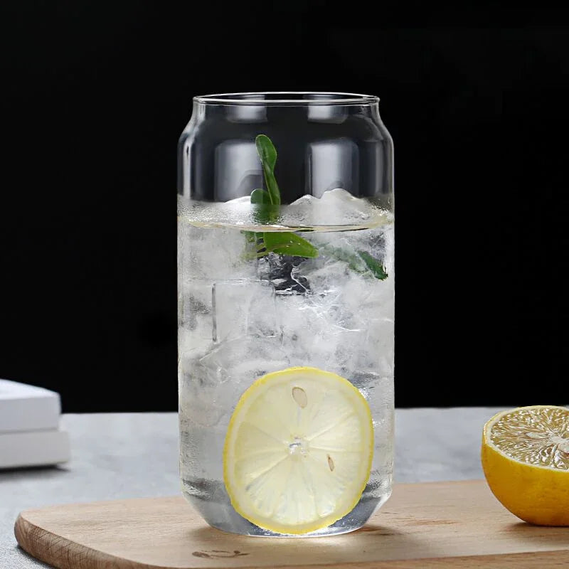 Clear glass with lemon slices and ice on a wooden cutting board against a black background