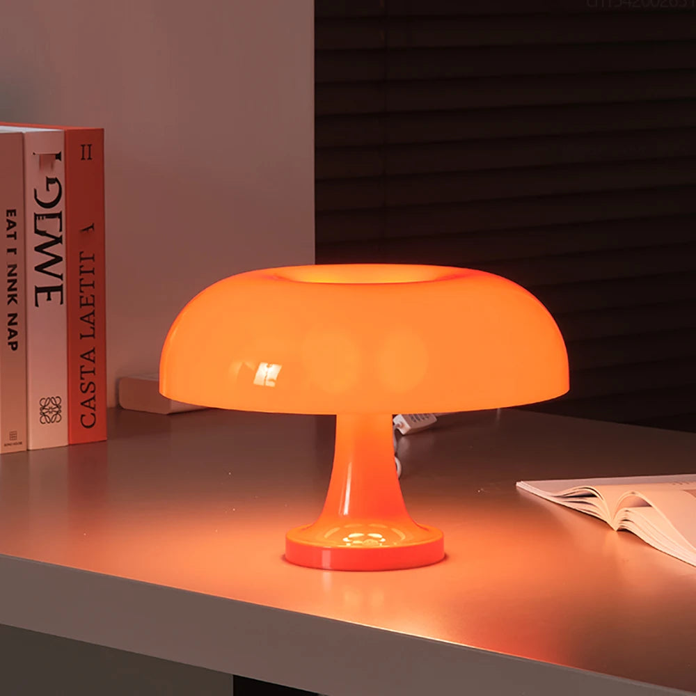 Orange table lamp on a desk with books and a magazine in the background