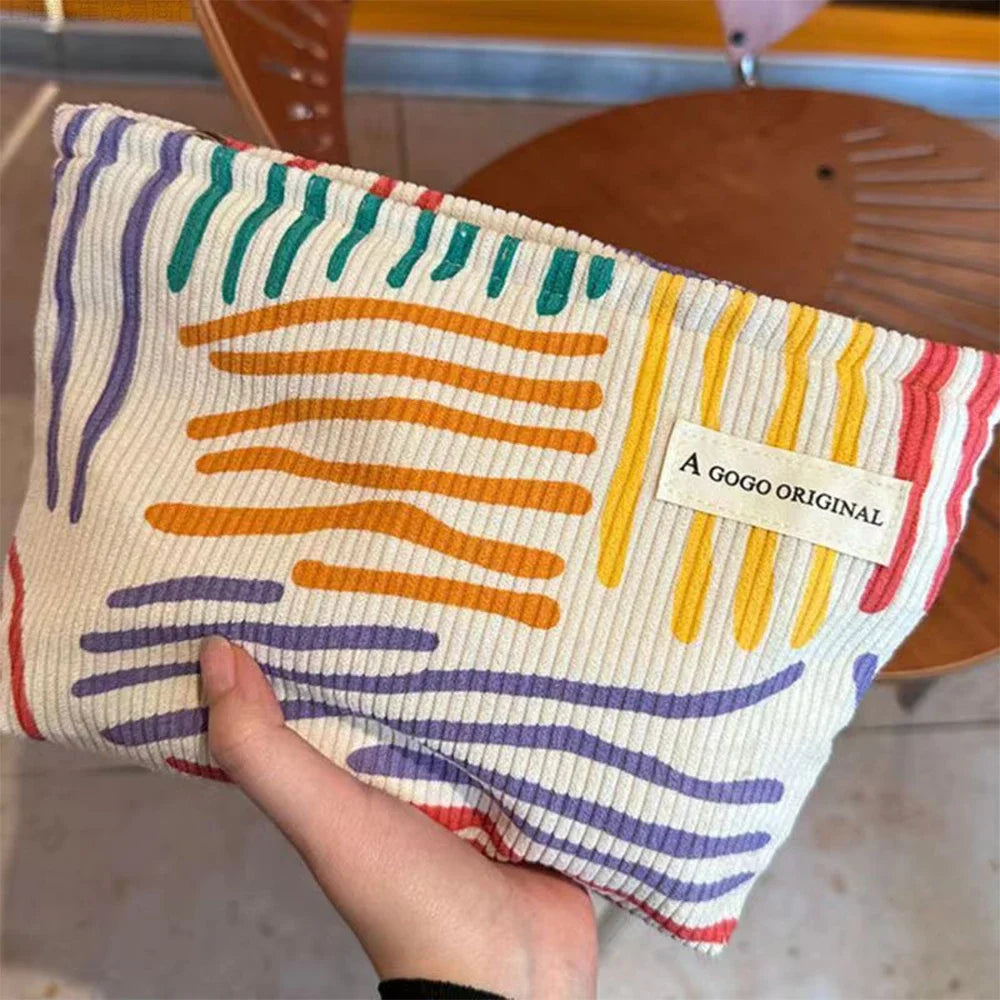 Colorful pouch with abstract patterns held by a hand, brand 'A GOGO ORIGINAL' visible.