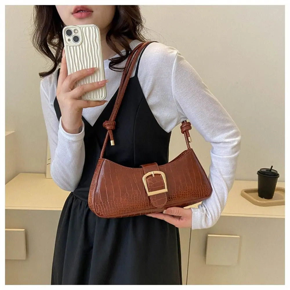 Person holding a brown handbag and a phone with a white case.