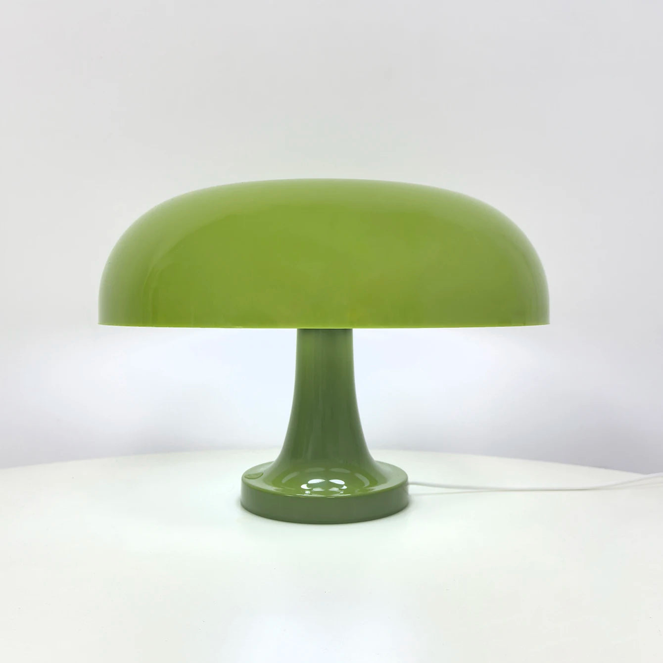 Green table lamp on a white surface with a light gray background