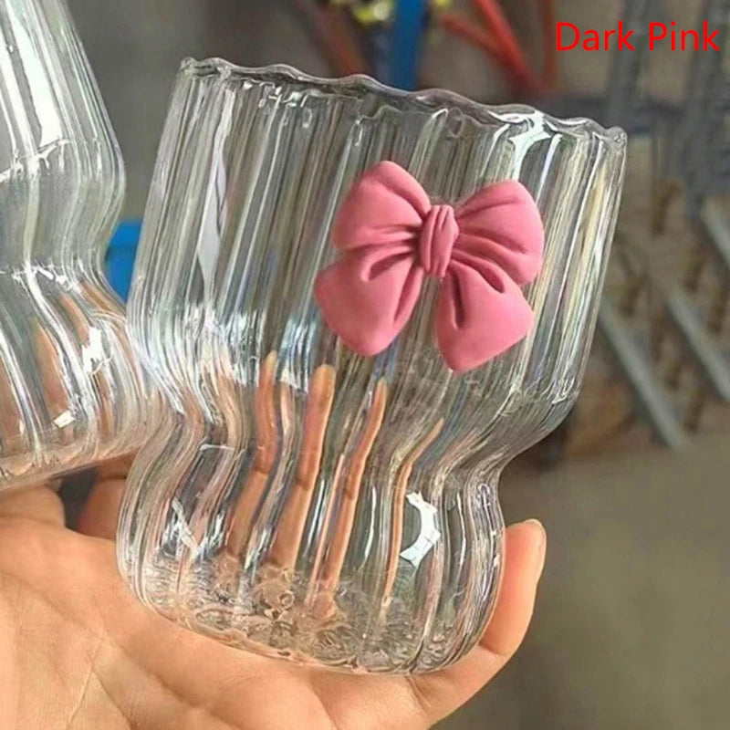 Clear glass with a pink bow held by a hand against a blurred background