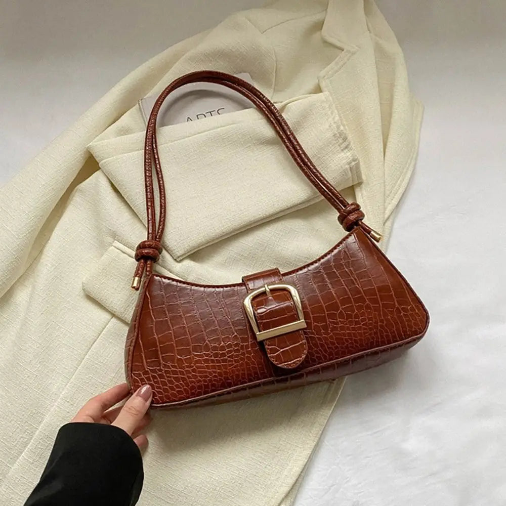 Brown handbag with gold buckle on a beige coat
