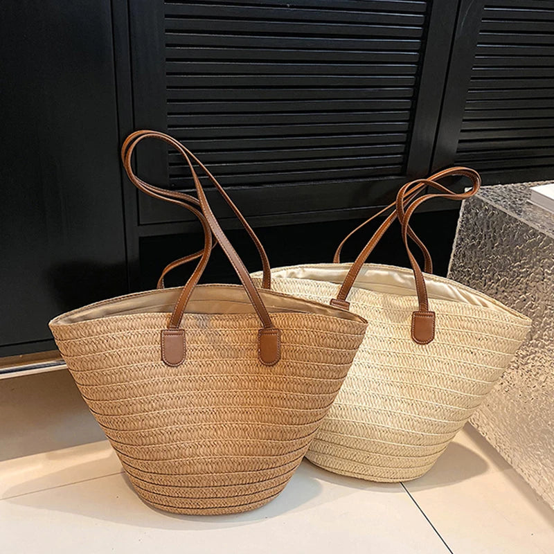 Two straw bags with brown handles on a light surface.