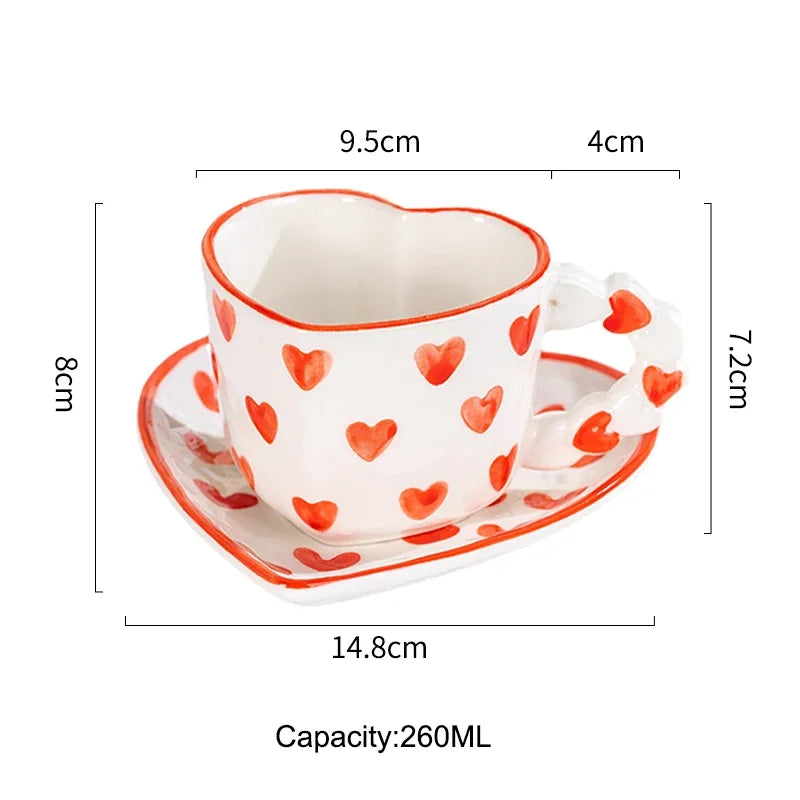 Heart-shaped cup with saucer featuring red heart patterns, shown with measurements on a white background.