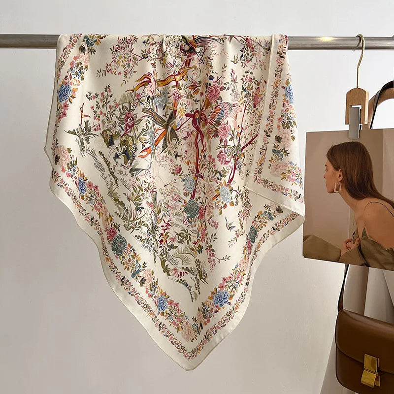 Floral and bird patterned scarf draped over a rack with a brown handbag in the background.
