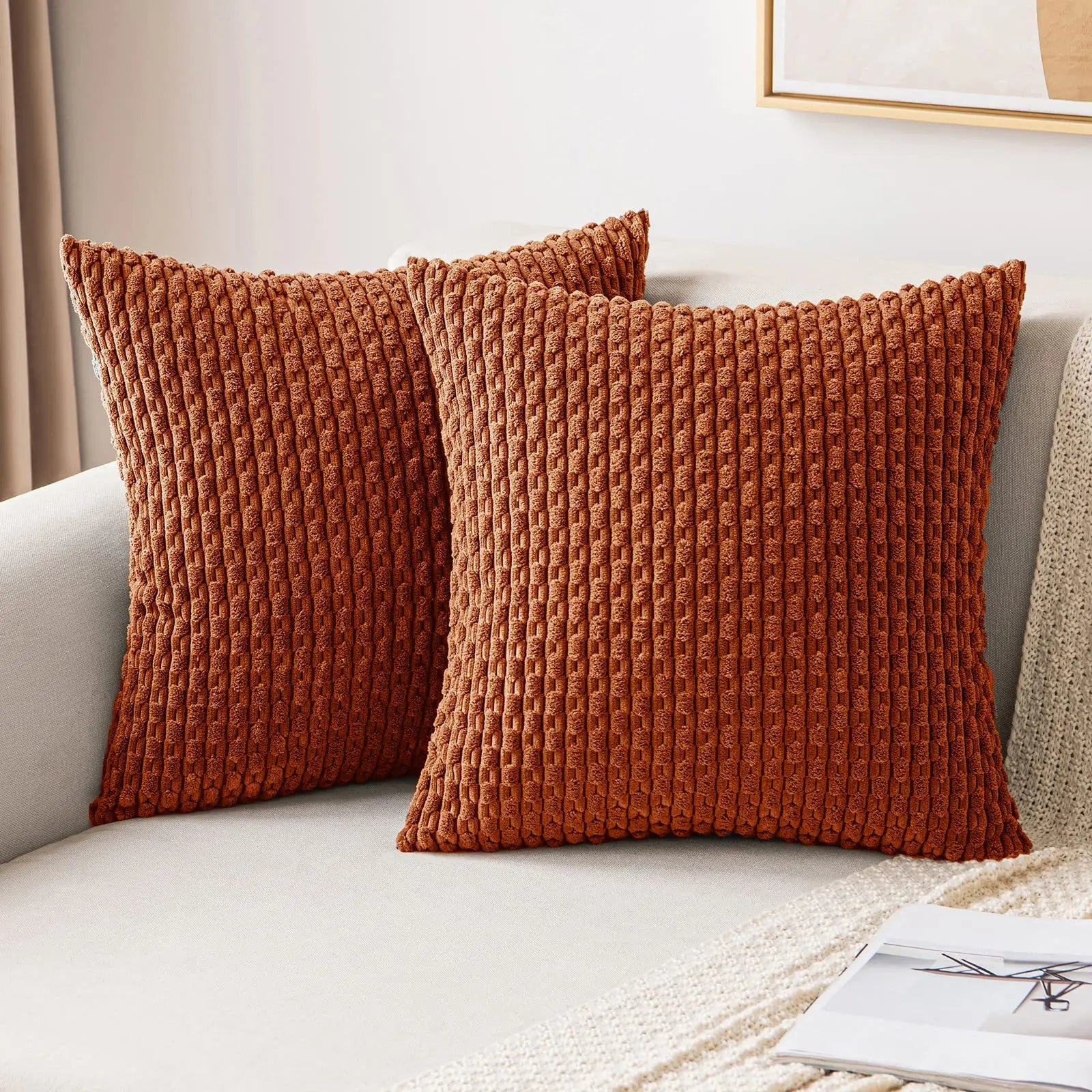 Two brown textured pillows on a light-colored sofa.