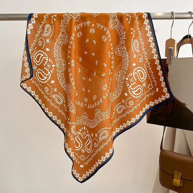 Orange bandana with white patterns draped over a mannequin against a neutral background