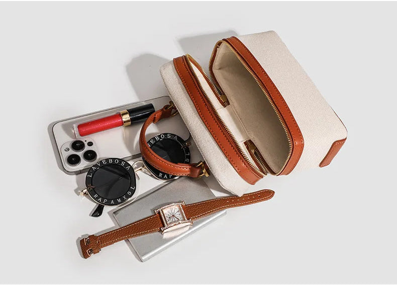 Open beige pouch with brown accents containing a phone, watch, and other items on a white background.