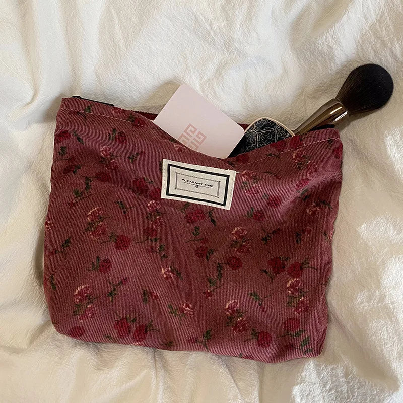 Floral makeup bag with a brush on a white textured surface