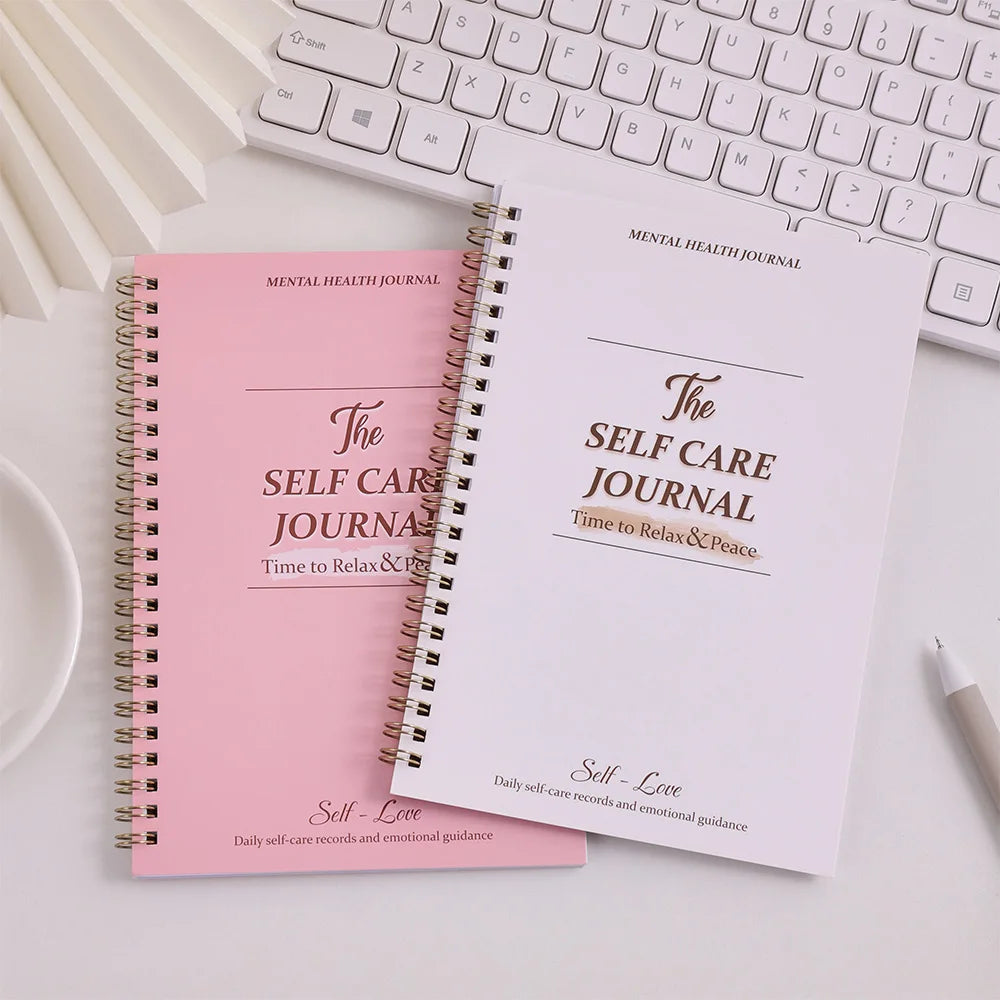 Two self-care journals on a desk with a keyboard