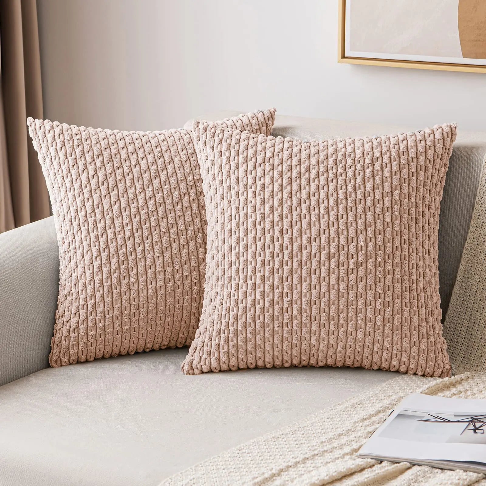 Two textured beige pillows on a sofa with a neutral background