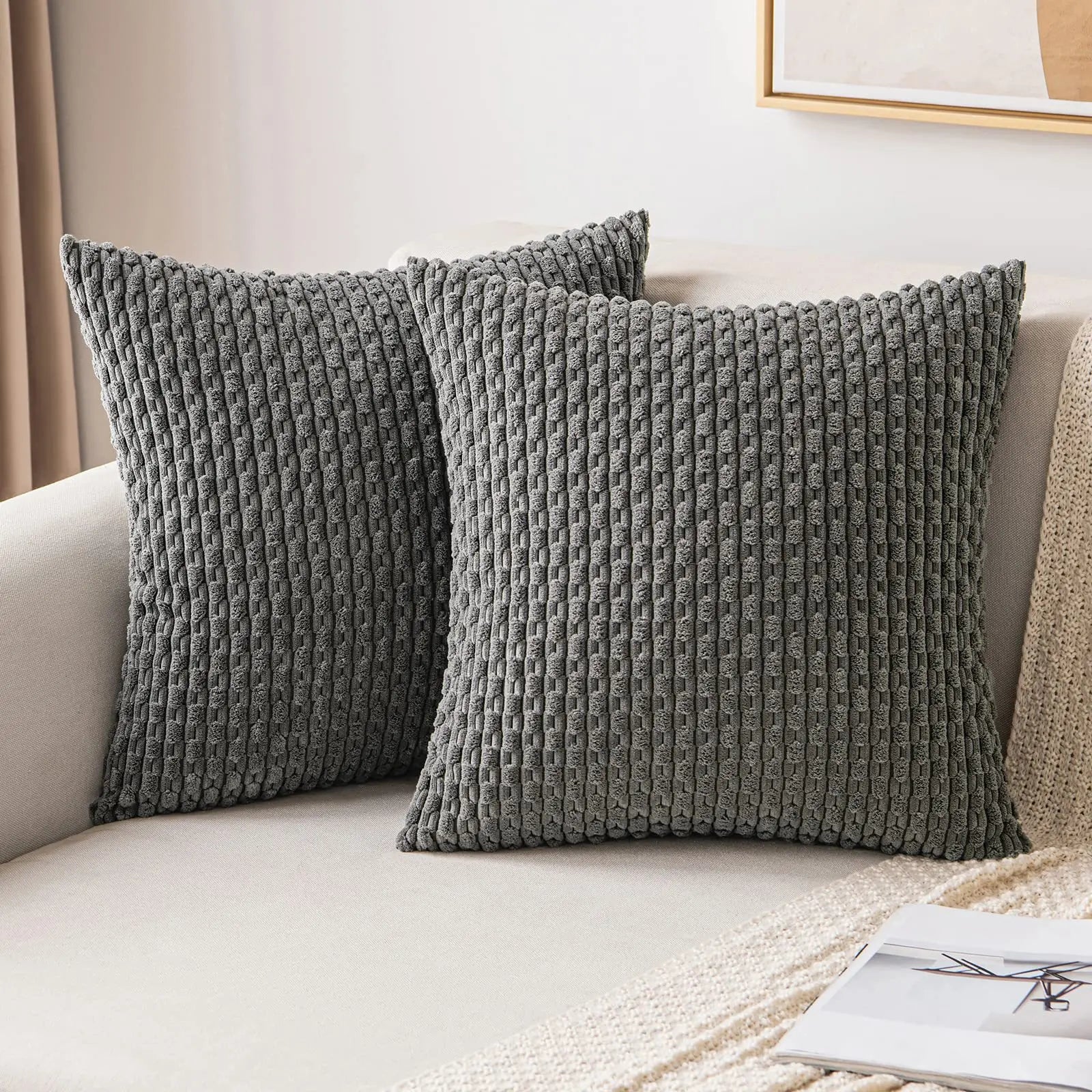 Two textured gray pillows on a beige sofa with a neutral background