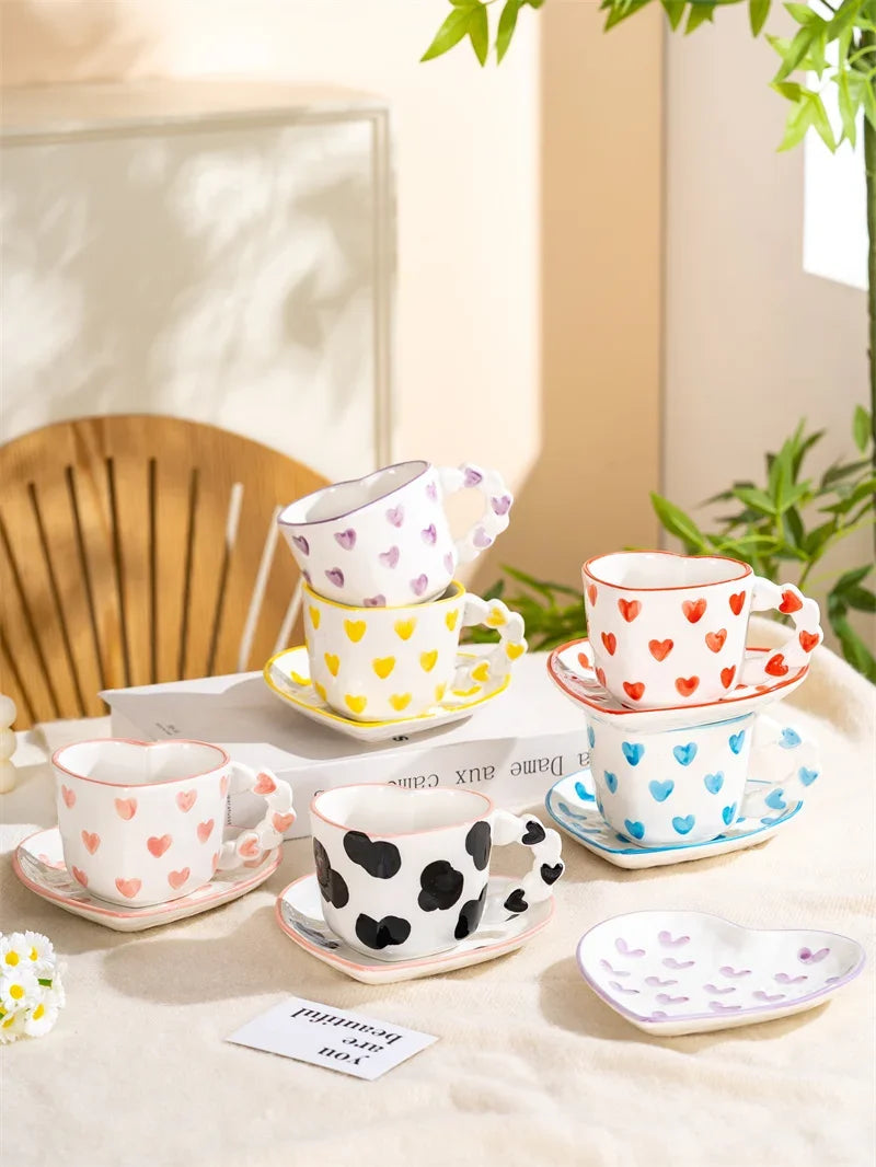 Set of colorful ceramic cups and saucers on a table with a plant in the background