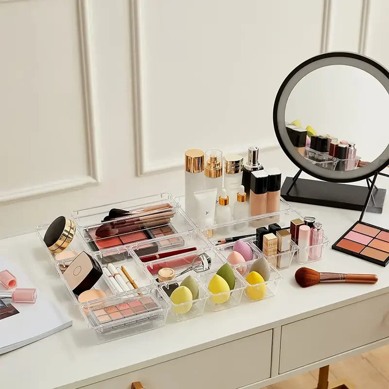 Makeup products on a vanity table set in clear containers with a round mirror.