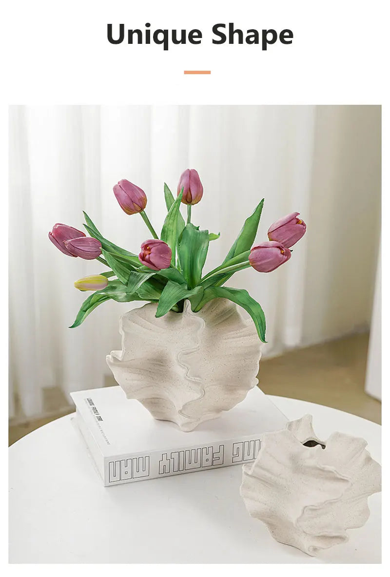 Uniquely shaped vase with pink tulips on a white surface