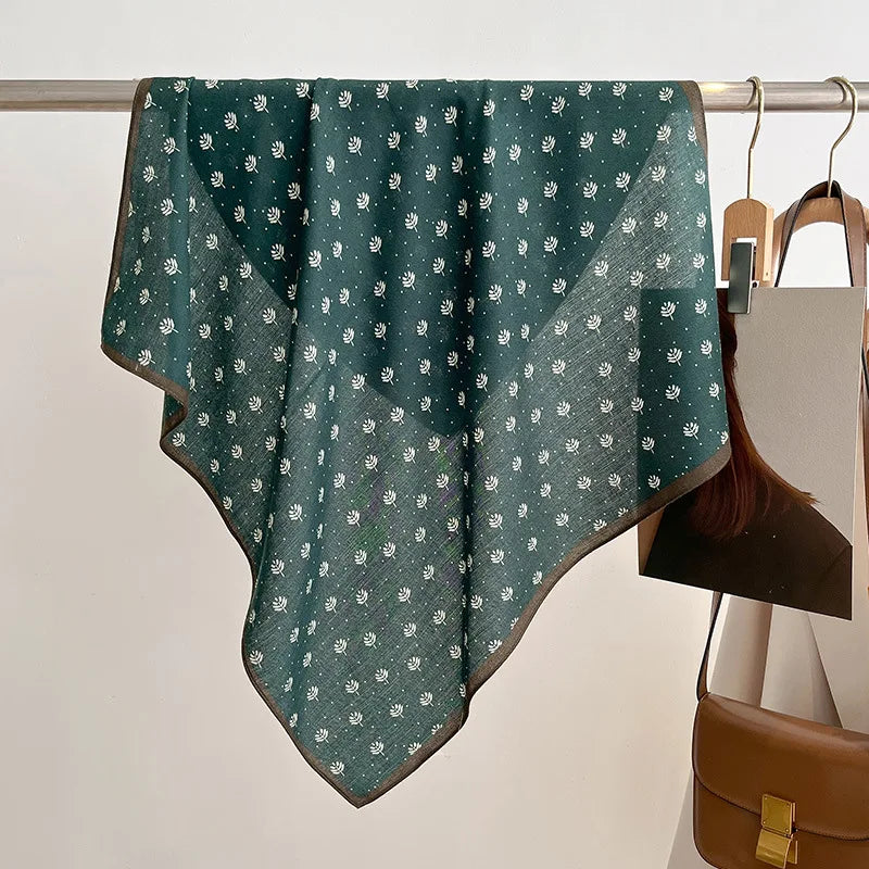 Green patterned scarf draped over a rack with a brown bag below.