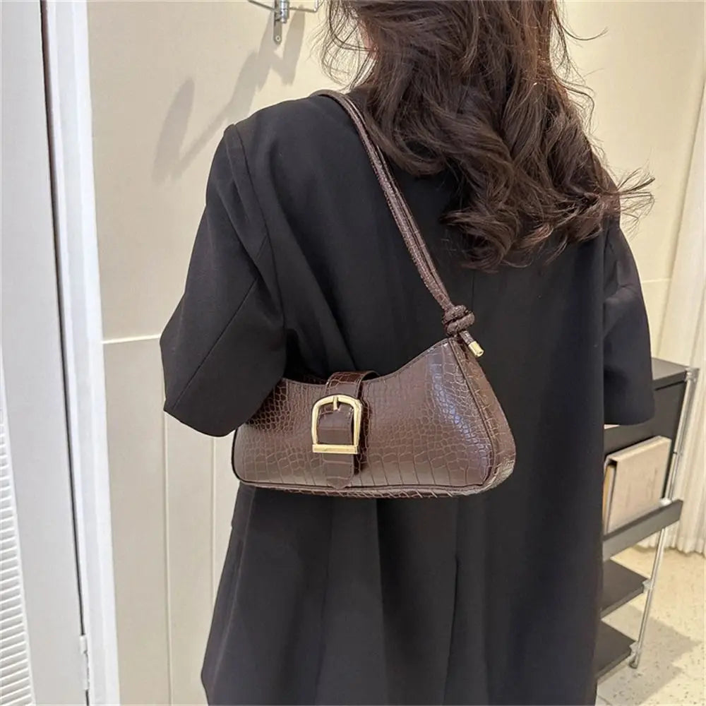Person wearing a black coat with a brown handbag featuring a gold buckle.