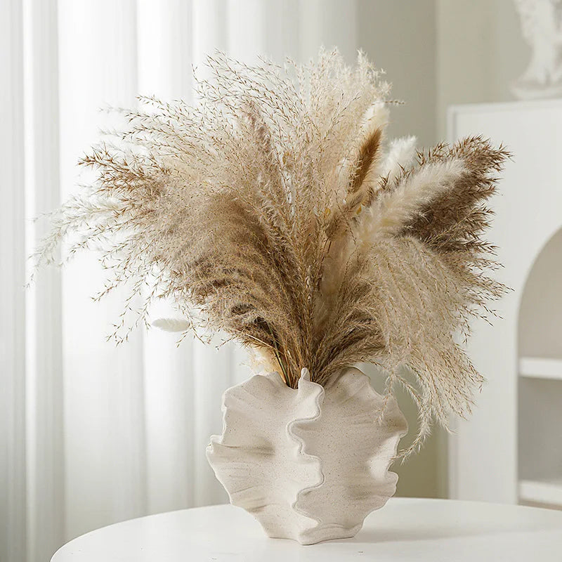 Decorative coral vase with dried pampas grass against a neutral background