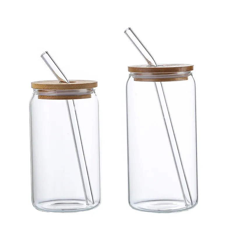 Two clear glass jars with wooden lids and straws on a white background