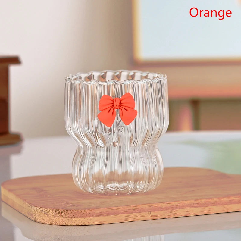 Clear glass candle holder with a orange bow on a wooden surface